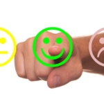 Bewertung Smileys Hand zeigt auf grünen zufriedenen Smiley