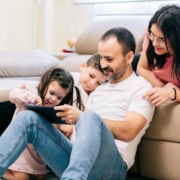 Eltern spielen mit Kindern auf der Coach am Tablet - mehr Zeit für die Familie